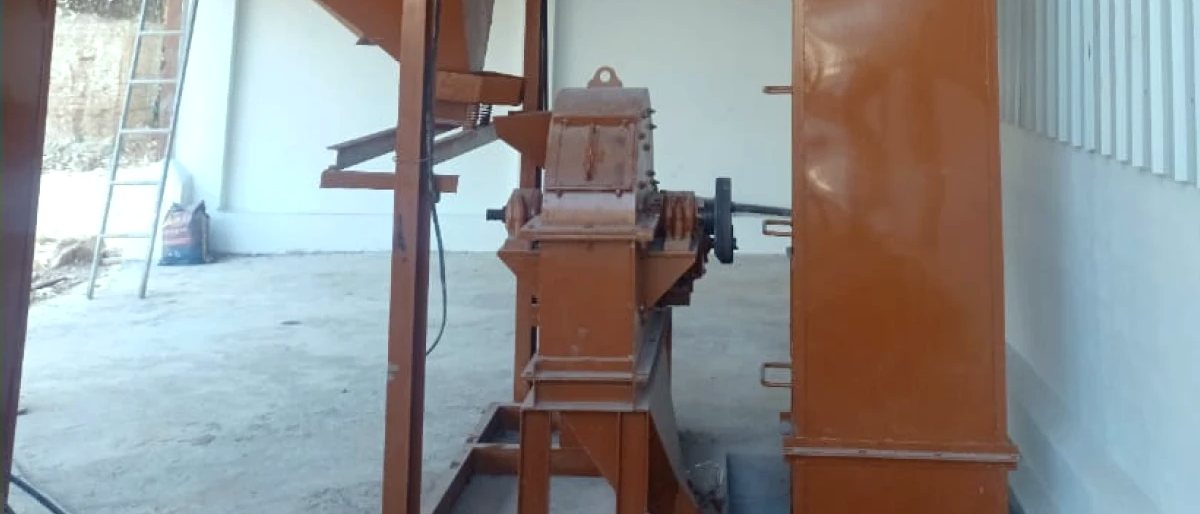 Jaw crusher and bucket elevator in red-oxide primer against the works wall